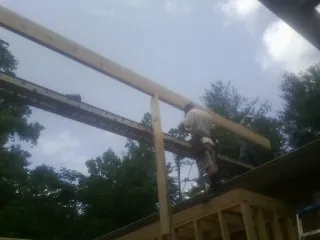 Carpenter setting a ridge beam over a new addition frame — Ice Dam Removal by Roofing Brothers in Milburn