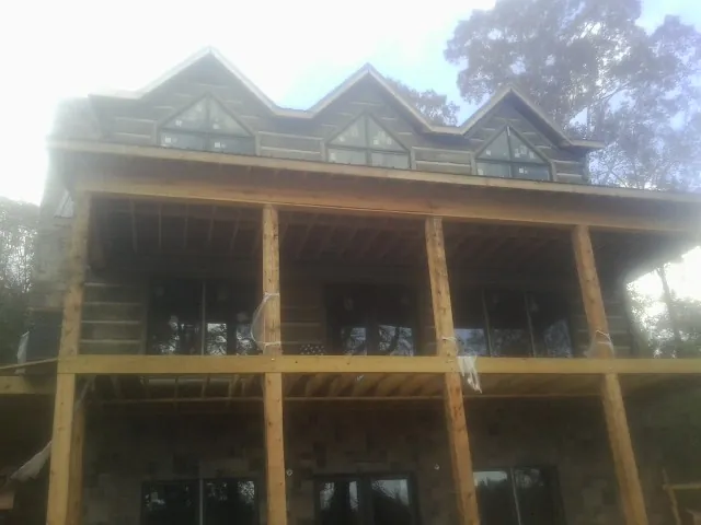 Dormers and porch framing on a large log home under construction — Roof Coating work by our crew in Milburn