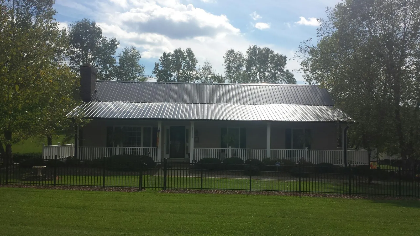 Gray metal roof on a brick ranch with a full width front porch — Gutter Guard Installation work by our crew in Milburn