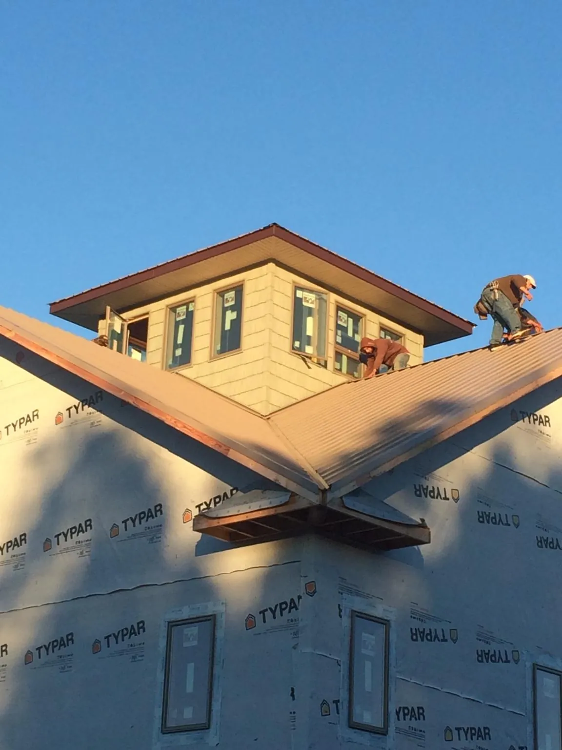 Roofers working around a rooftop cupola on a new metal roof at sunset — Roof Waterproofing in Milburn by Roofing Brothers